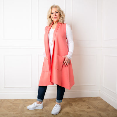 Casually styled sleeveless cardigan in coral pink worn by model